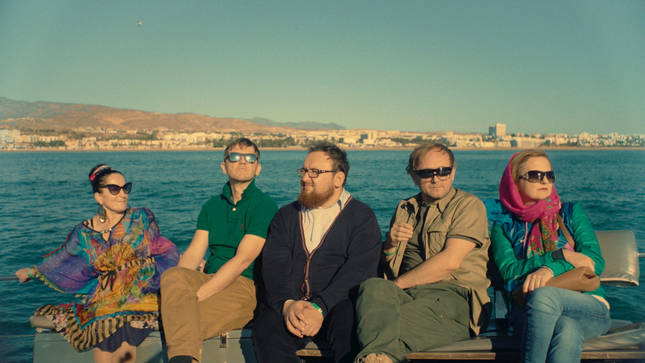 Kadr z filmu "All Inclusive" przedstawiający bohaterów filmu siedzących, w tle widać morze